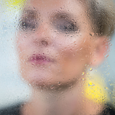 Monika Swindells partially obscured by a fogged glass, embodying themes of design, mindfulness, and connection in her work.