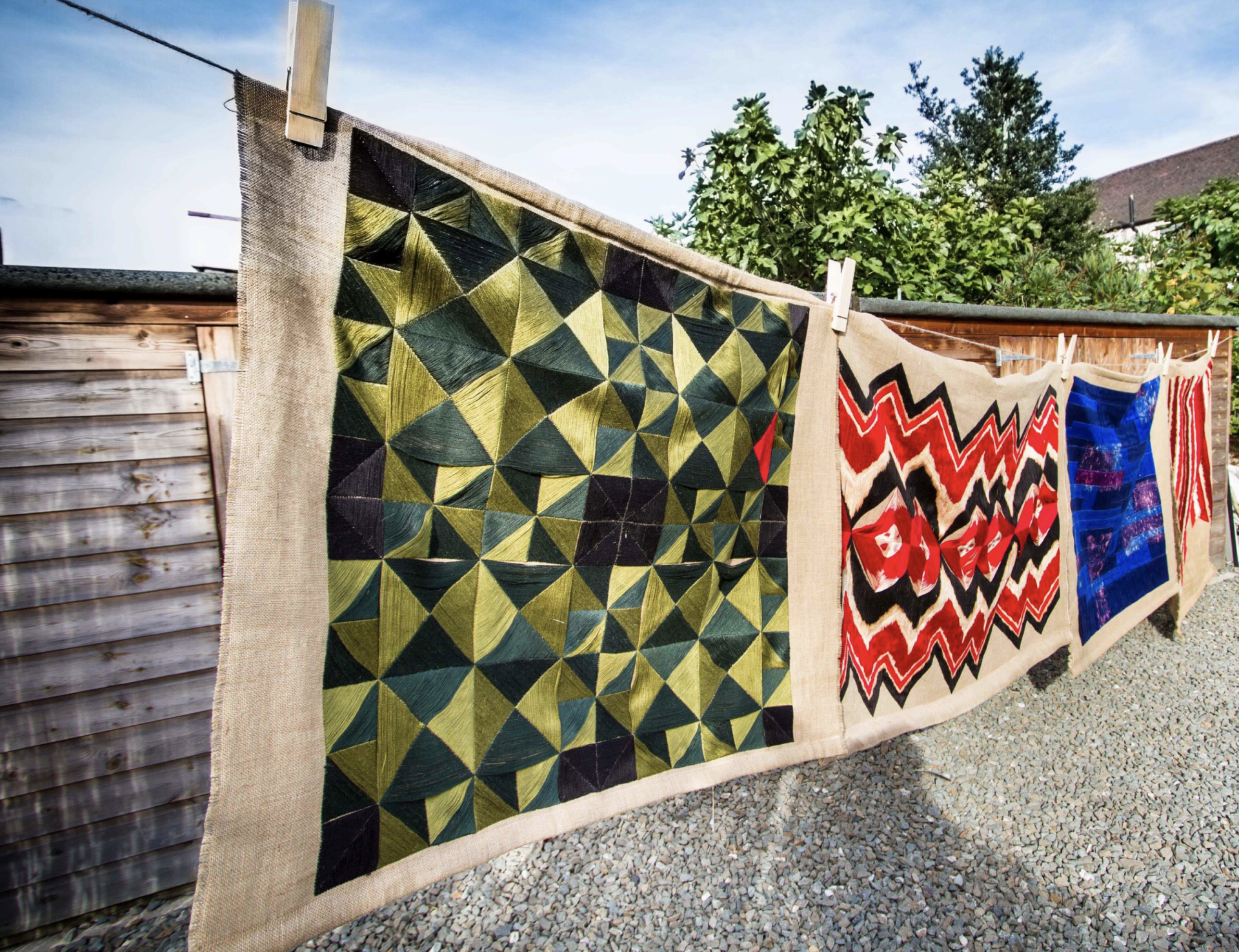 Large scale contemporary wall hangings featuring traditional Slovakian embroidery techniques displayed outdoors, showcasing vibrant patterns and colors.