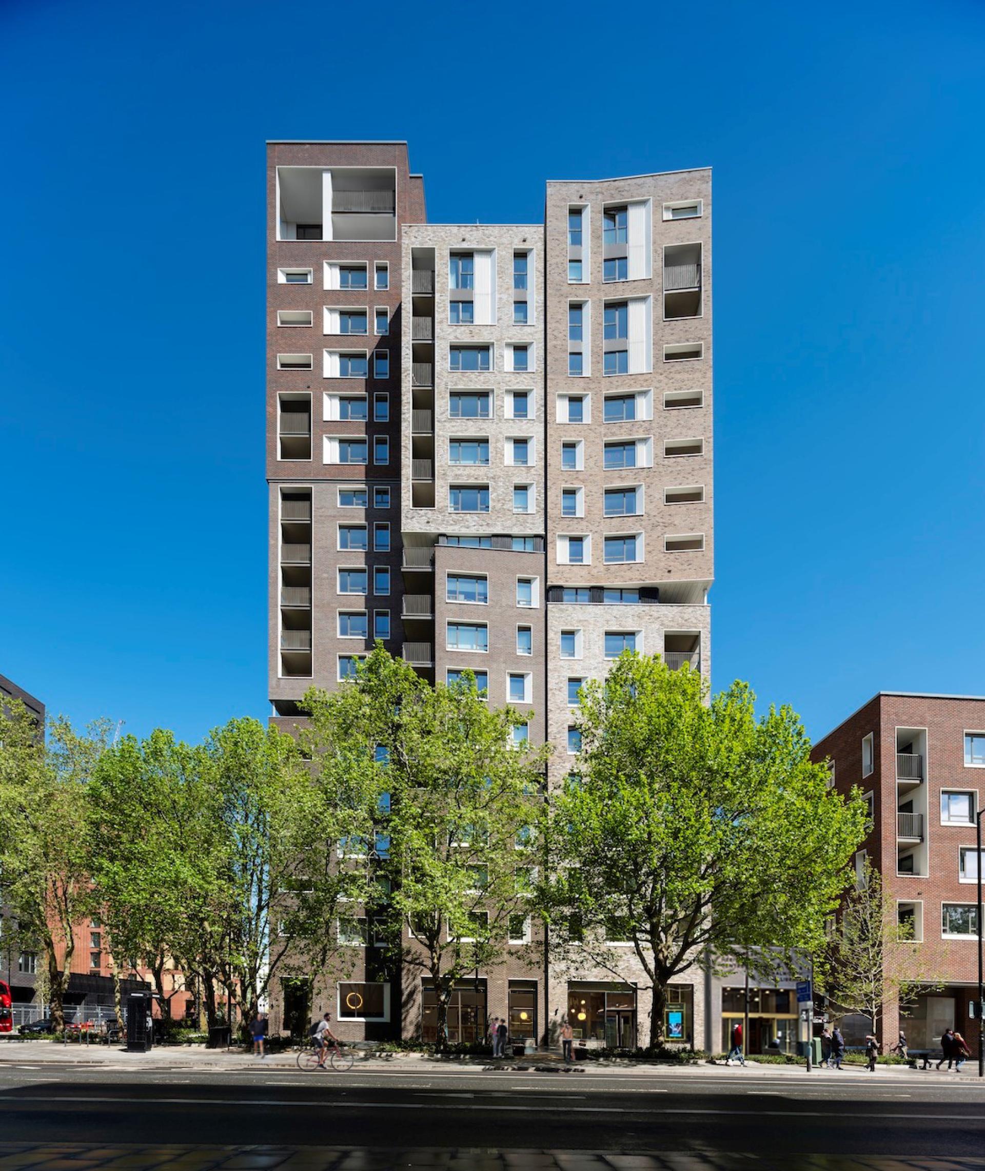 Modern residential building featuring unique architectural design with green trees in front, nominated for RIBA 2022 Stirling Prize.