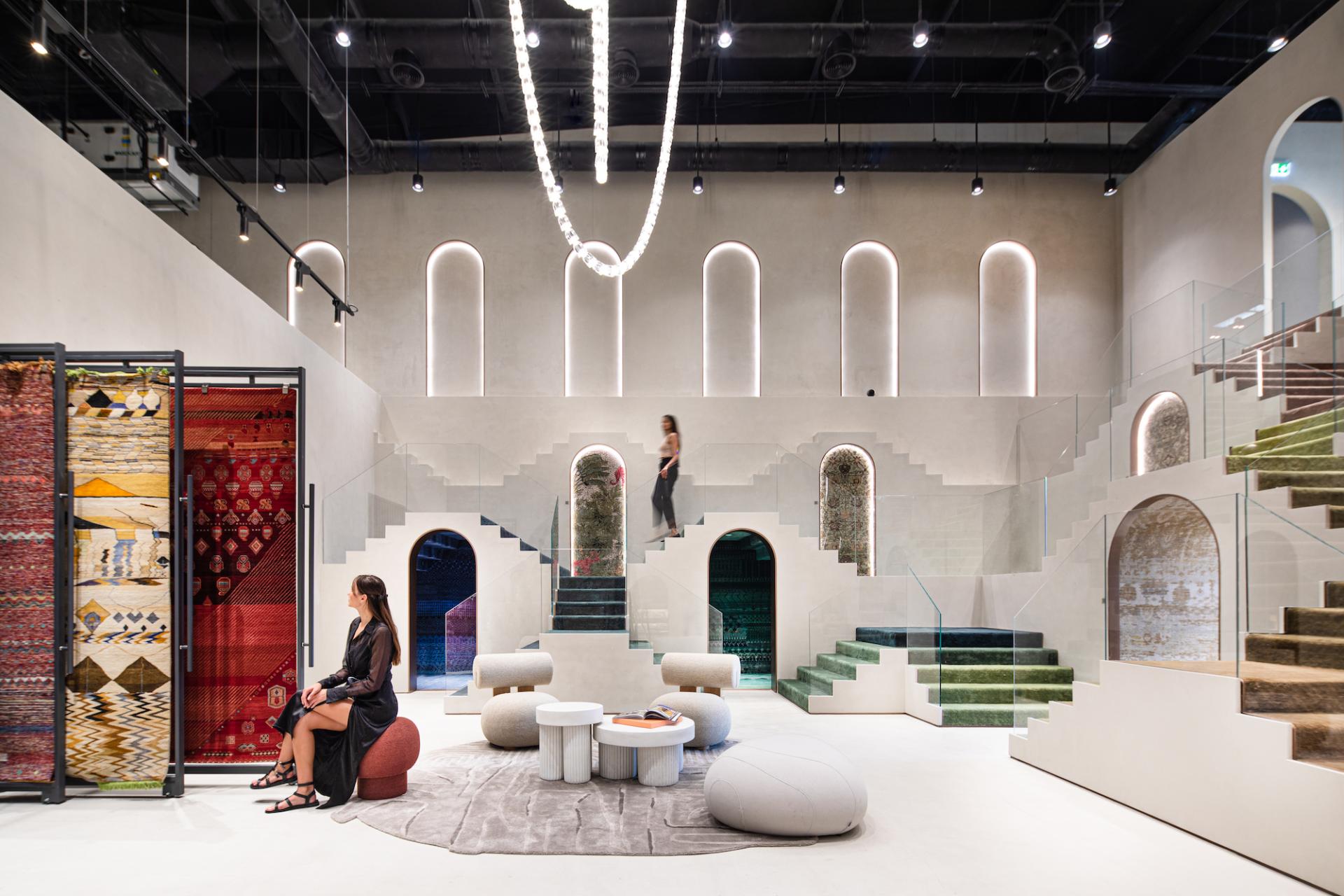 Contemporary showroom inspired by Rajasthani architecture, featuring colorful rugs and modern seating arrangements.