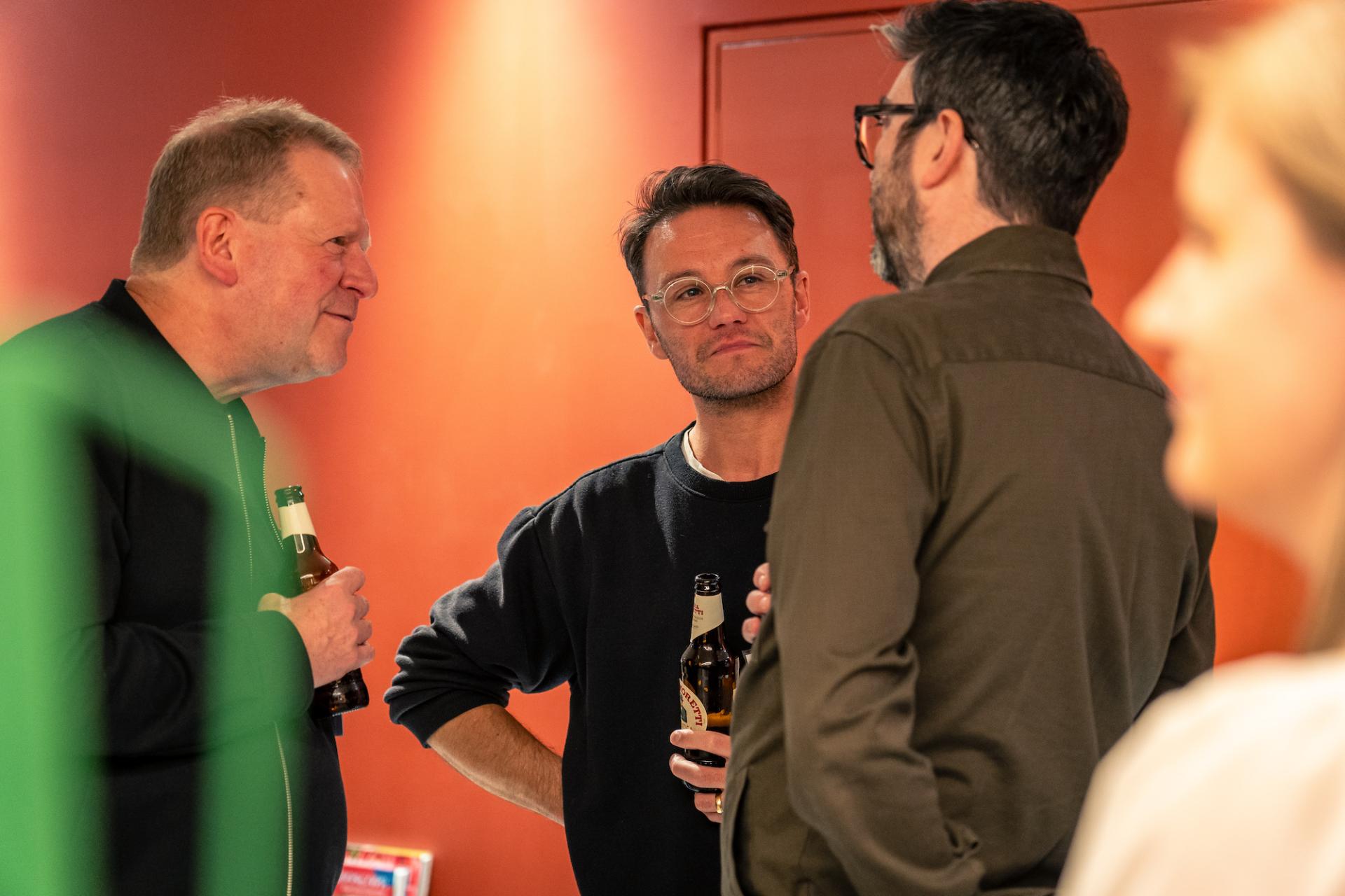 Three professionals engage in conversation at a Glasgow property event, showcasing a positive atmosphere.