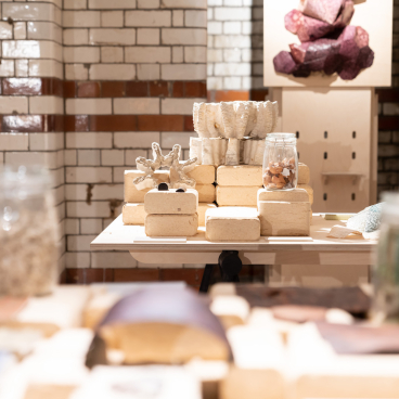 Exhibition setup featuring diverse materials and textures in a gallery, celebrating the From The Ground Up initiative.