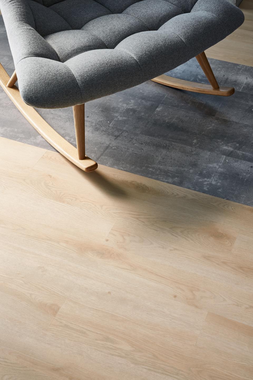 Modular resilient flooring featuring a wood-like design and a contemporary rocking chair, highlighting Tarkett's sustainable materials.