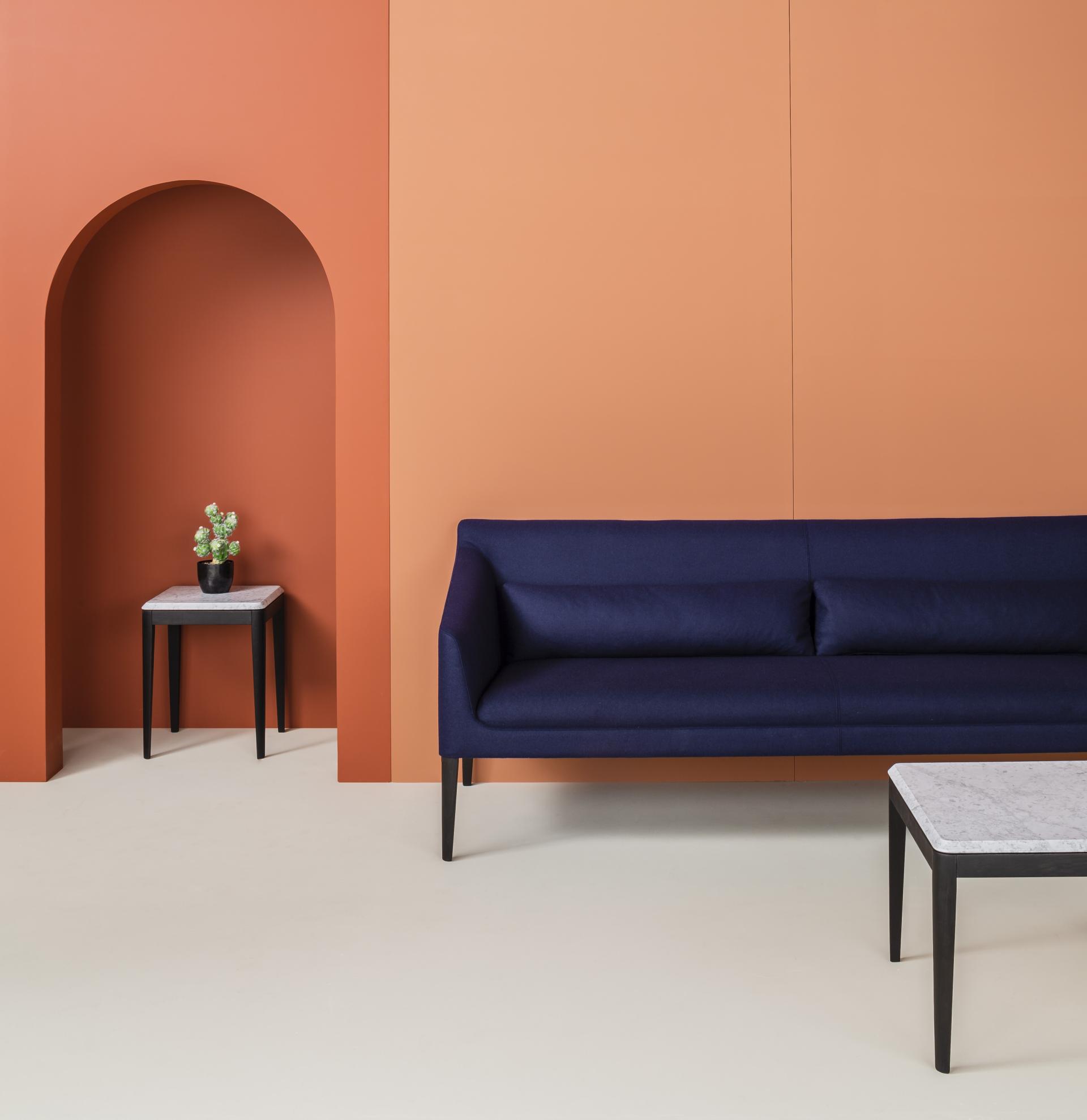 Stylish navy sofa and modern marble table against an orange backdrop, showcasing the versatility of the Kyoto collection.