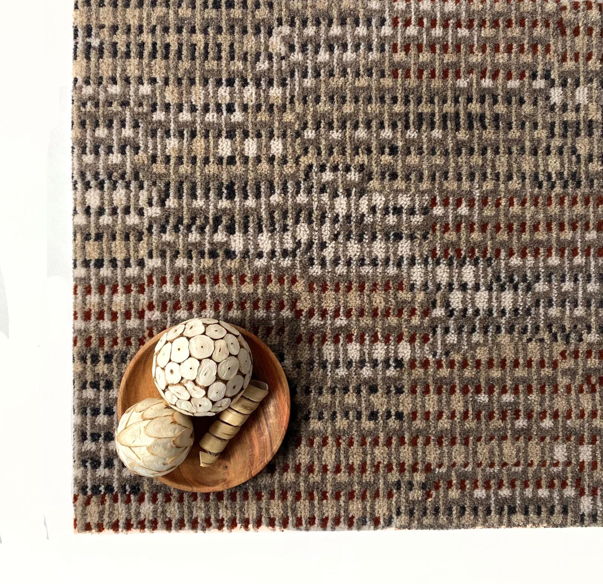 Craft-inspired Macramé carpet by Newhey featuring a textured pattern, complemented by decorative wooden items on a plate.