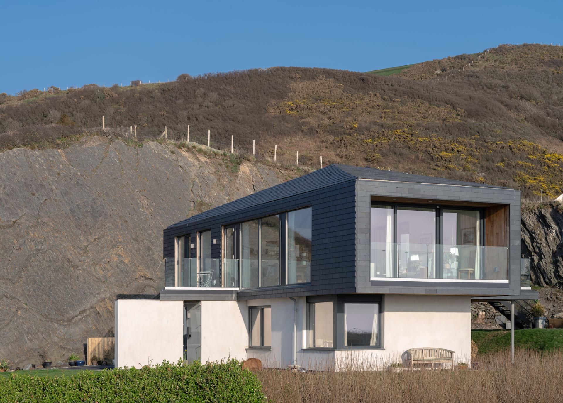 Modern coastal home featuring CUPACLAD 101 Logic slate cladding, harmonizing with the natural landscape and nearby cliffs.