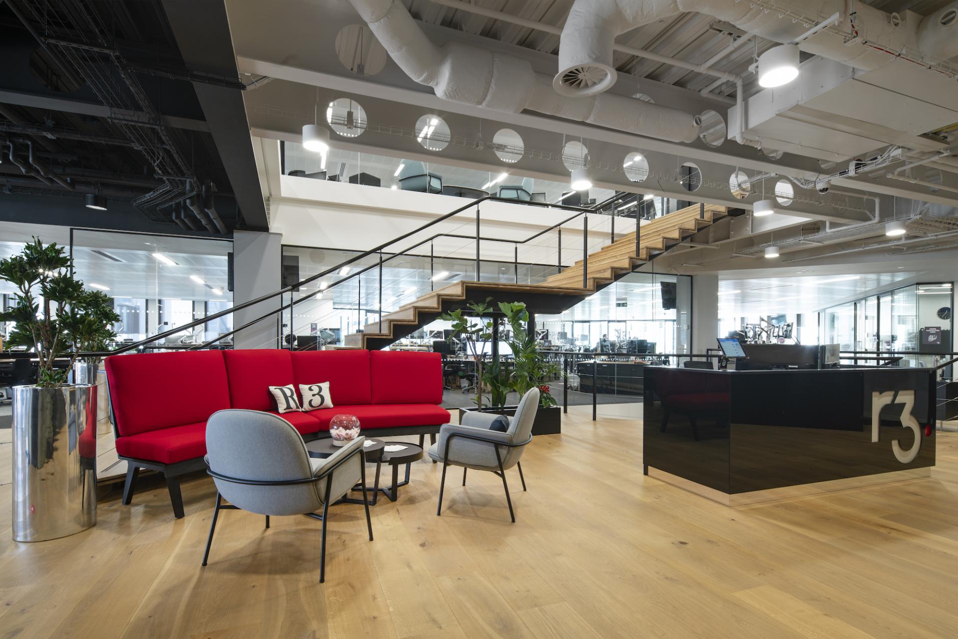 Modern office interior featuring vibrant red seating and sleek design elements, embodying data-driven workplace solutions by Morgan Lovell.