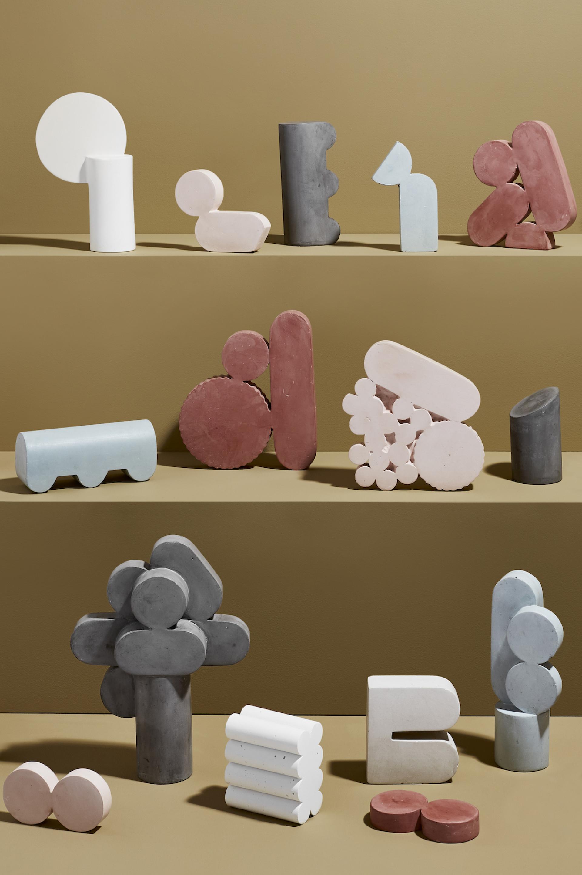 Sculptures by Vic Wright displayed on a shelf, featuring abstract shapes and vibrant colors, showcasing her sculptural artistry.