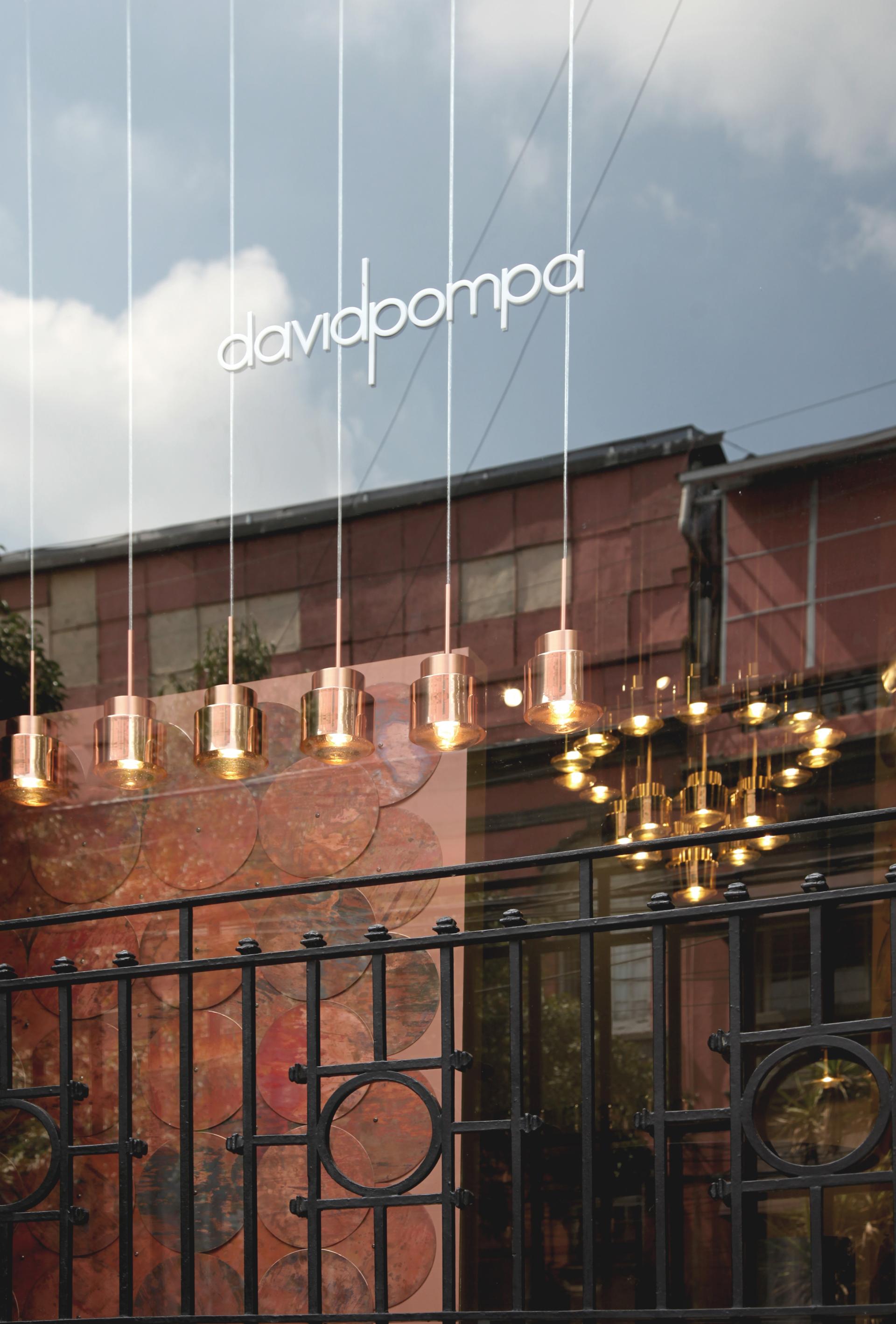 Showroom entrance of Davidpompa in Mexico City, featuring modern lighting and displays of local materials.