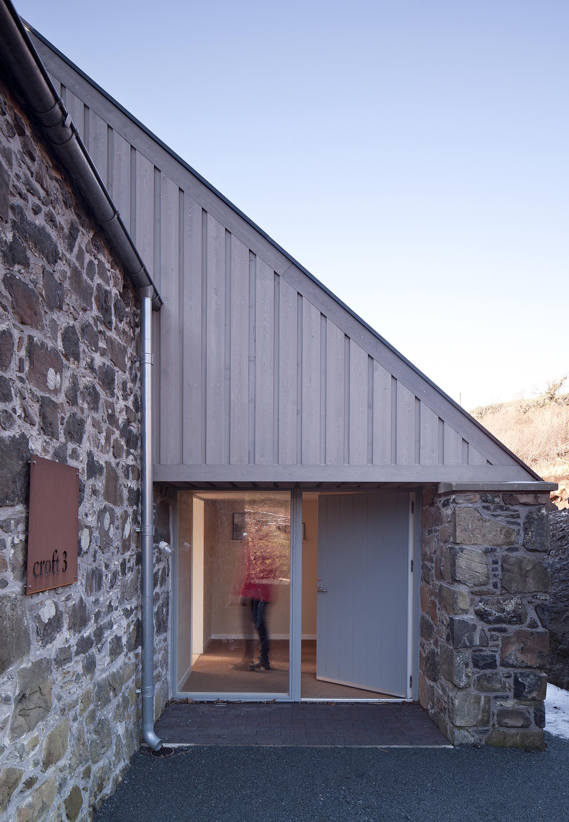 Restored croft 3 entrance on the Isle of Mull, showcasing modern design blending with traditional stonework.