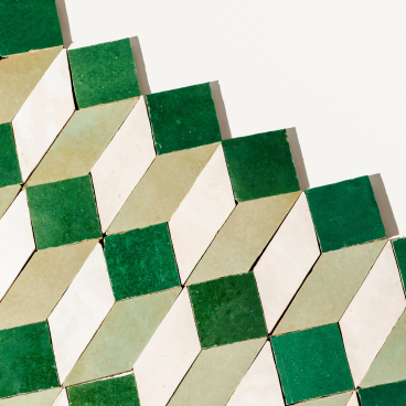 Vibrant green and cream geometric zellige tiles arranged in a playful, modern pattern for dynamic interior design.