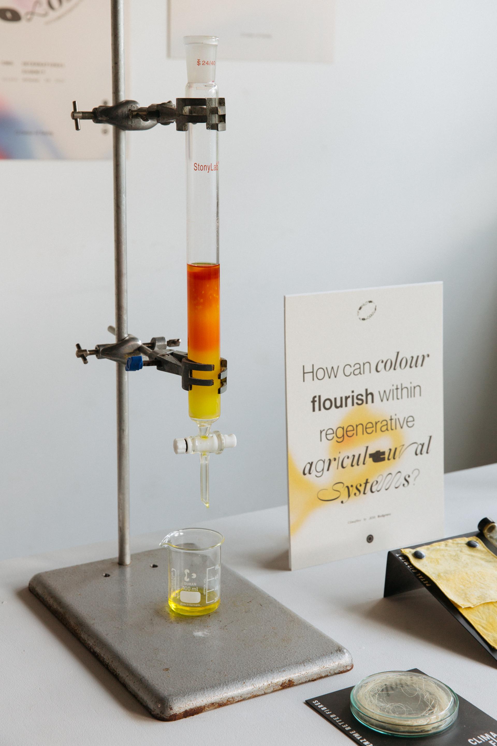 Laboratory setup featuring a test tube with colorful liquids, exploring color applications in regenerative agriculture design.