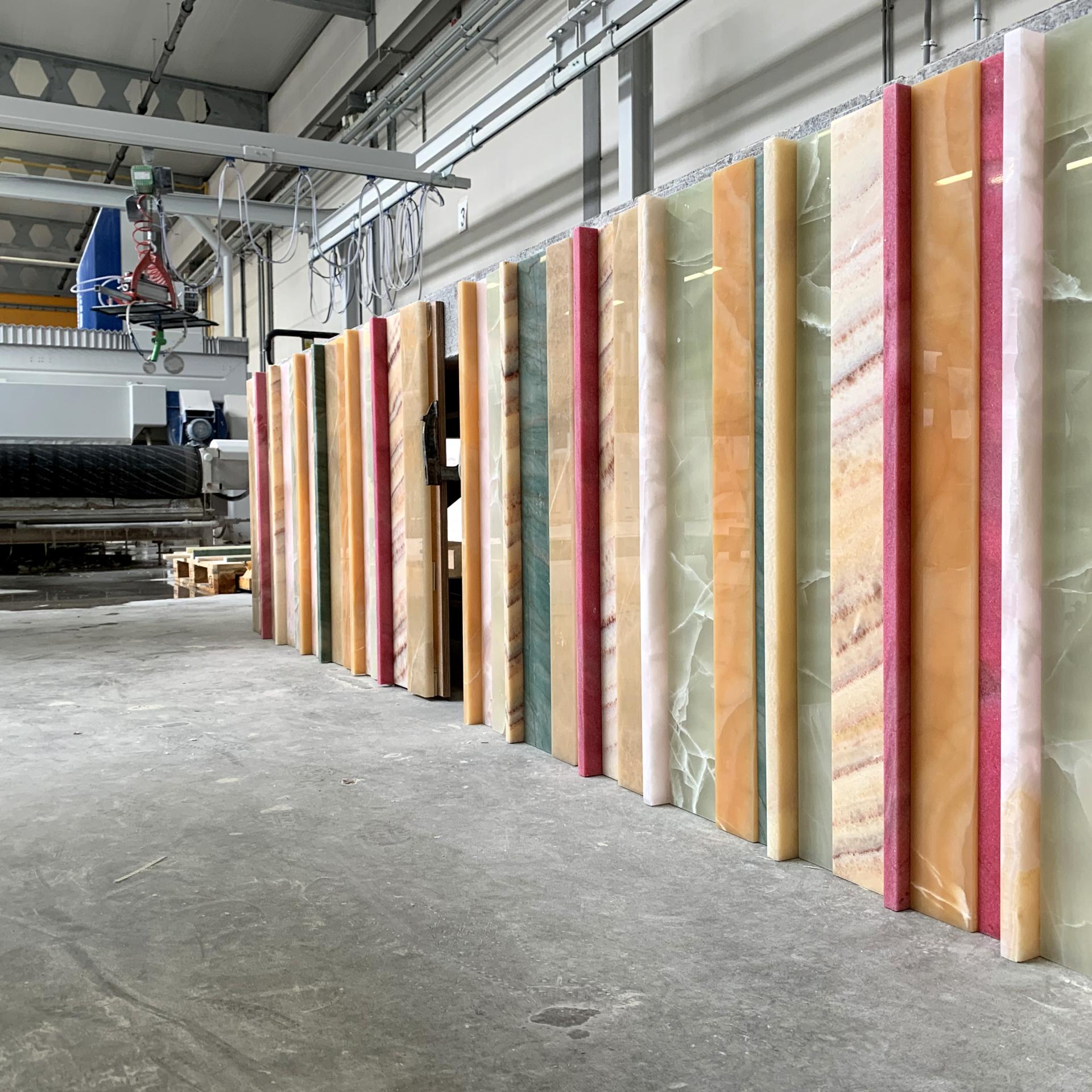 Vibrant slabs of colored Onyx showcased in a natural stone workshop, highlighting SolidNature's craftsmanship for office and retail design.