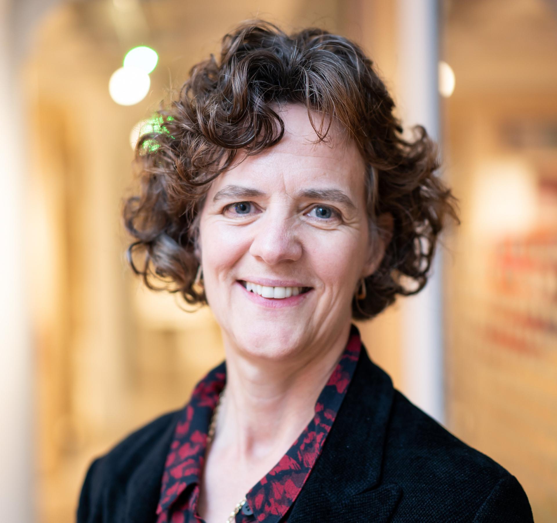 Professional woman smiling, representing optimism in the future of education post-pandemic, with a modern background.