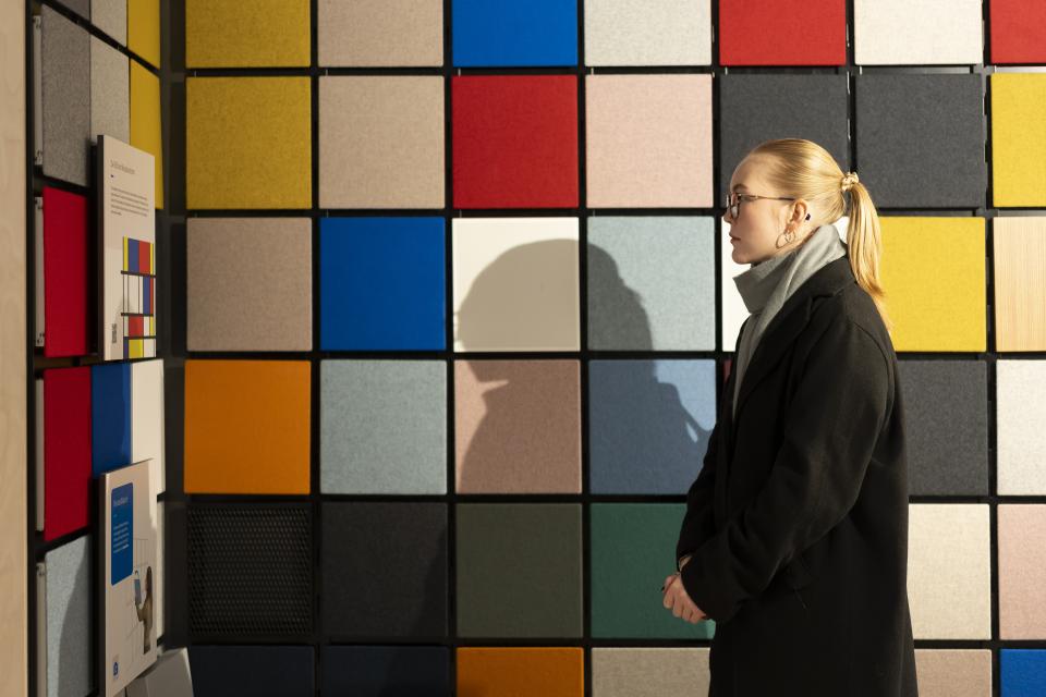 A woman observes a colorful acoustic panel display at Material Source Studio, celebrating three years of creativity.