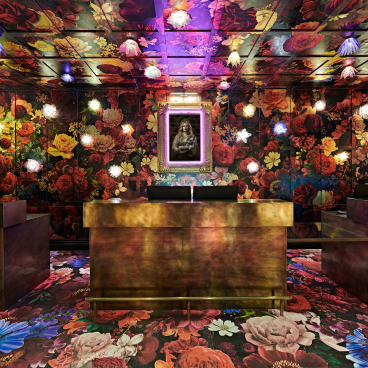 Vibrant floral decor and colorful lighting adorn the lobby of Naumi Studio Hotel, showcasing modern design and creativity.