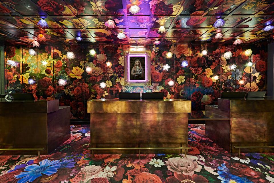 Vibrant floral decor and colorful lighting adorn the lobby of Naumi Studio Hotel, showcasing modern design and creativity.