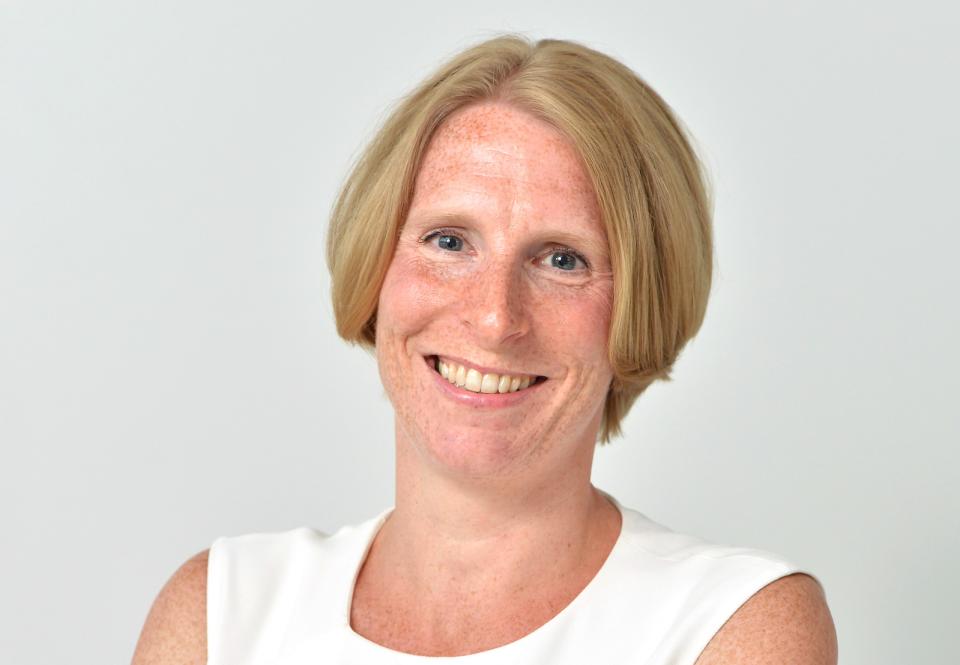 Smiling woman in a white top, representing innovation in luxury vinyl flooring by Karndean Designflooring.