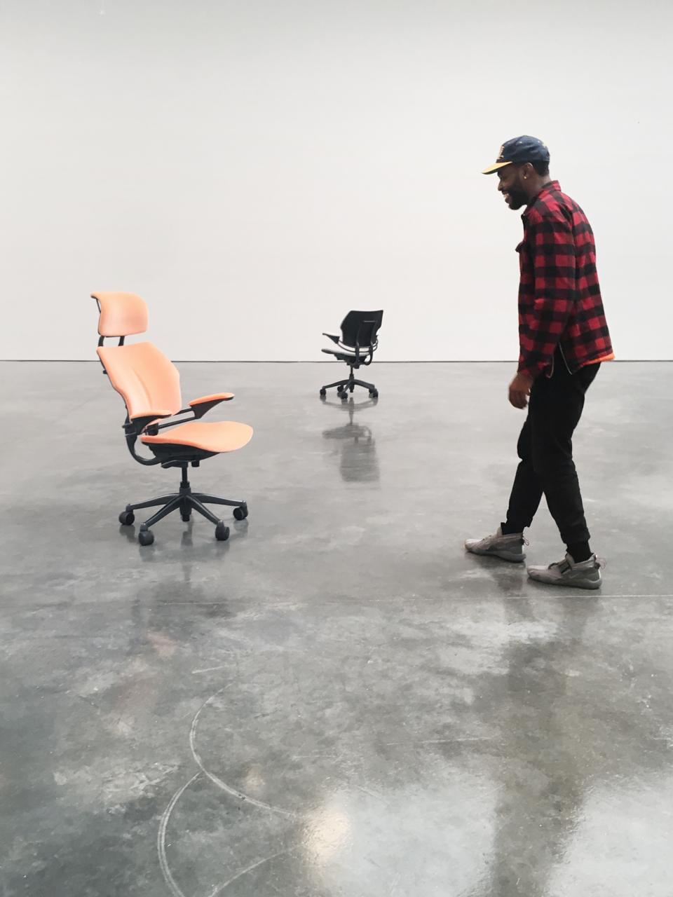 A person interacts with Humanscale Freedom chairs displayed in a minimalist gallery setting in New York City.