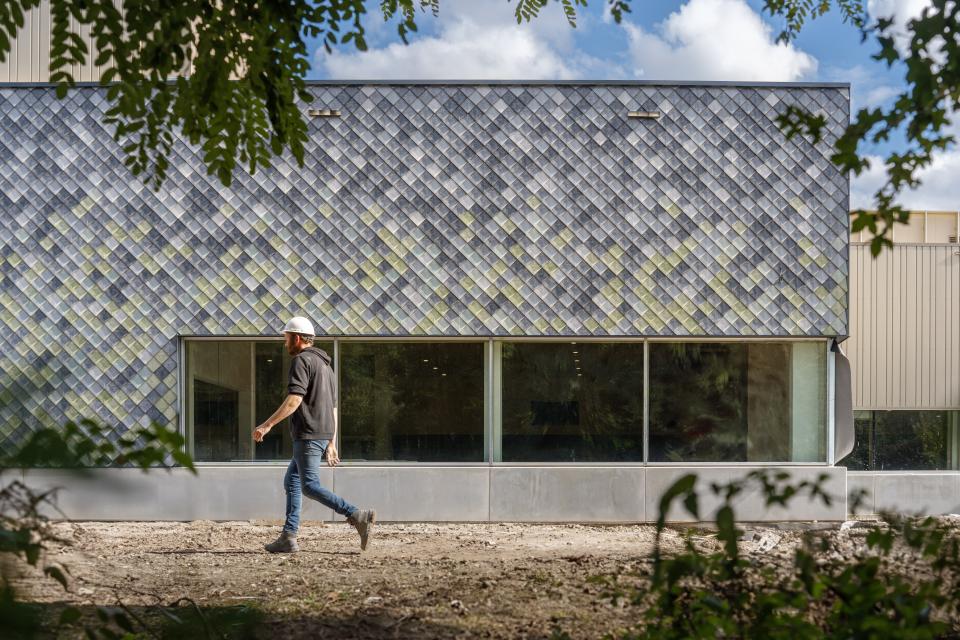 A construction worker walks by a building featuring innovative sustainable materials for circular construction.
