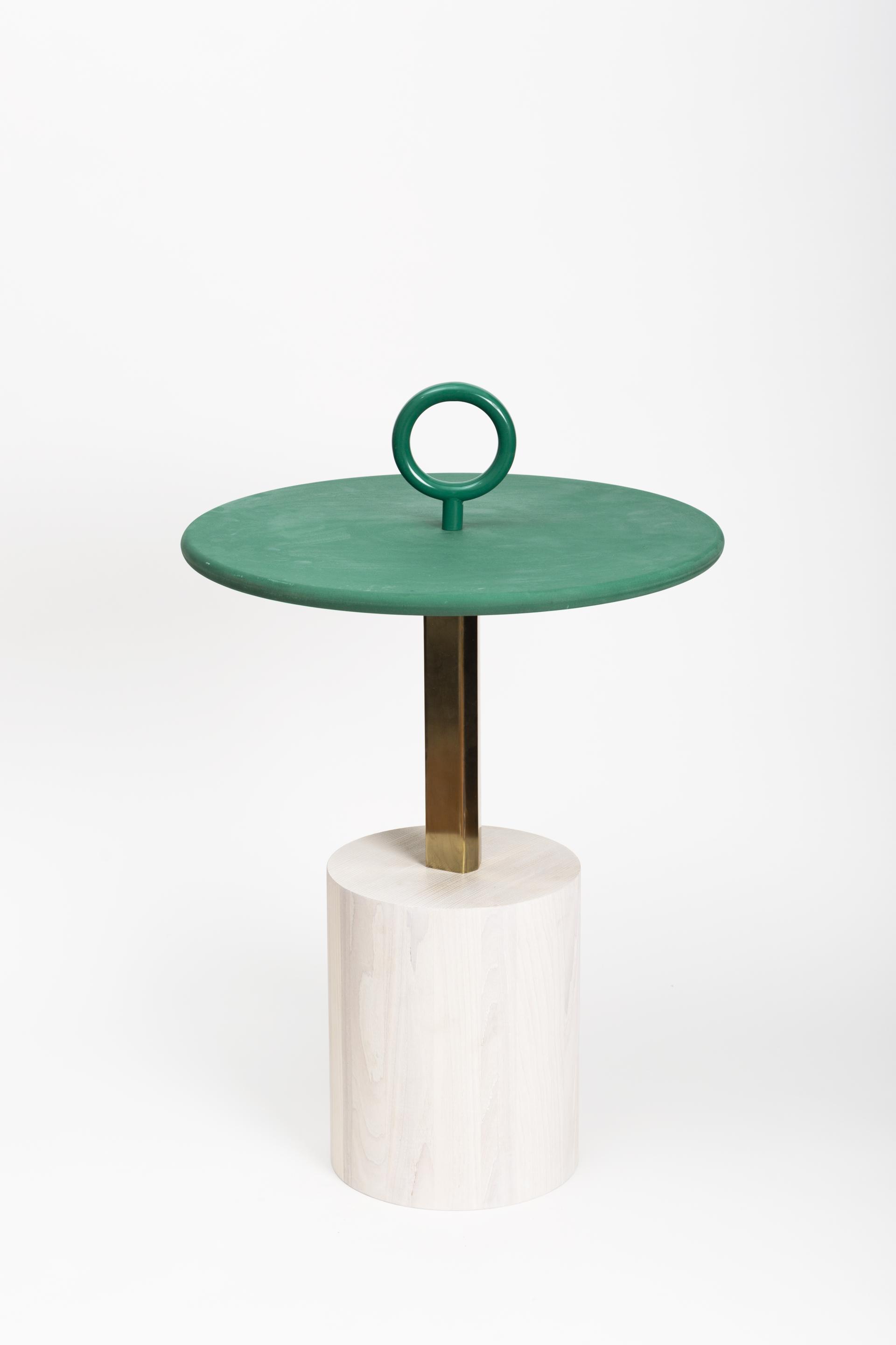 Contemporary green side table with a circular top, brass stem, and rounded wooden base, showcasing unique design elements.