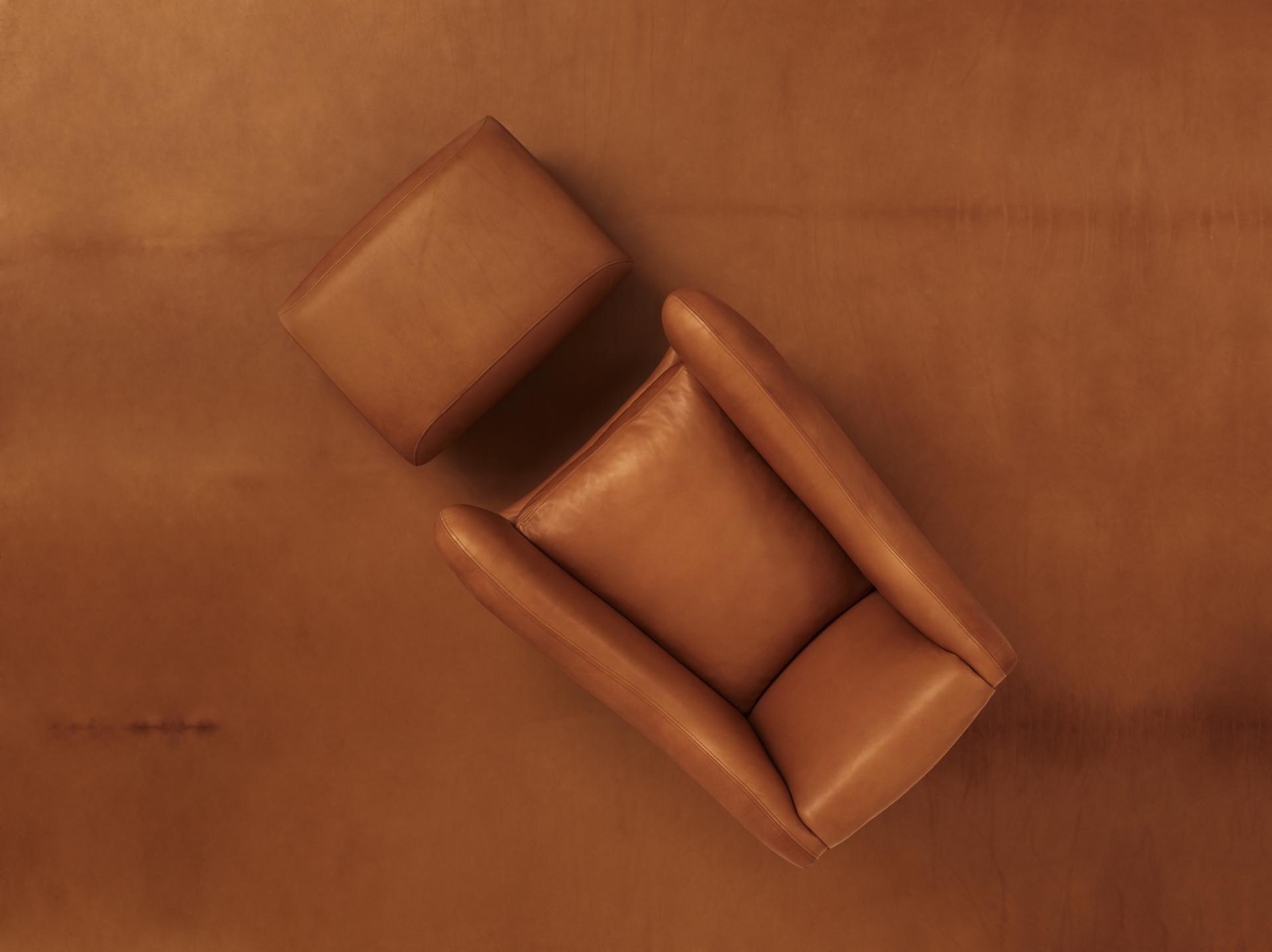 Matthew Hilton's Balzac armchair and ottoman in warm tan leather, celebrating 30 years of iconic design.