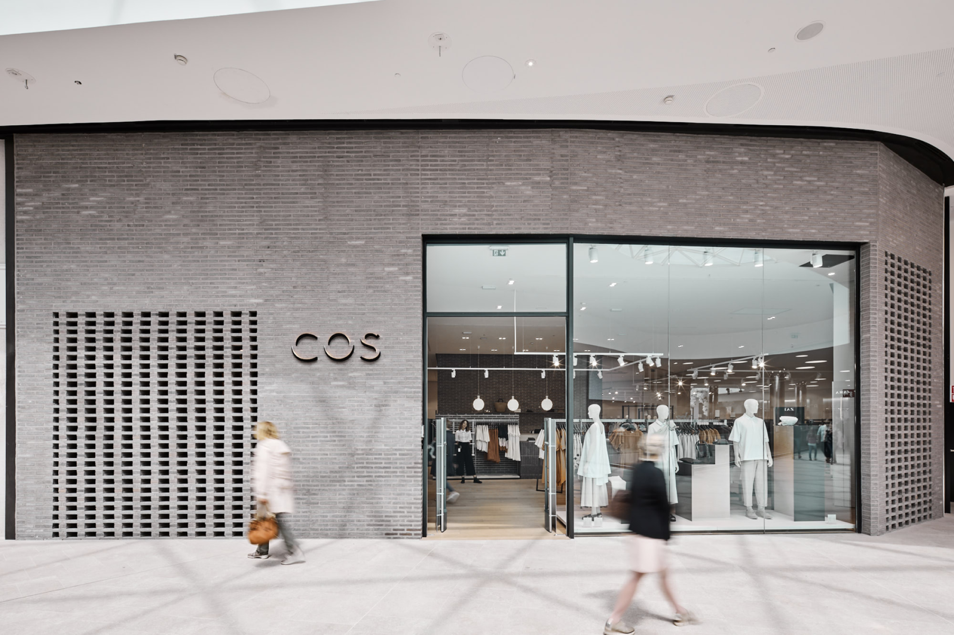 Modern boutique storefront displaying minimalist fashion in neutral tones, representing sustainable design and innovation in retail.