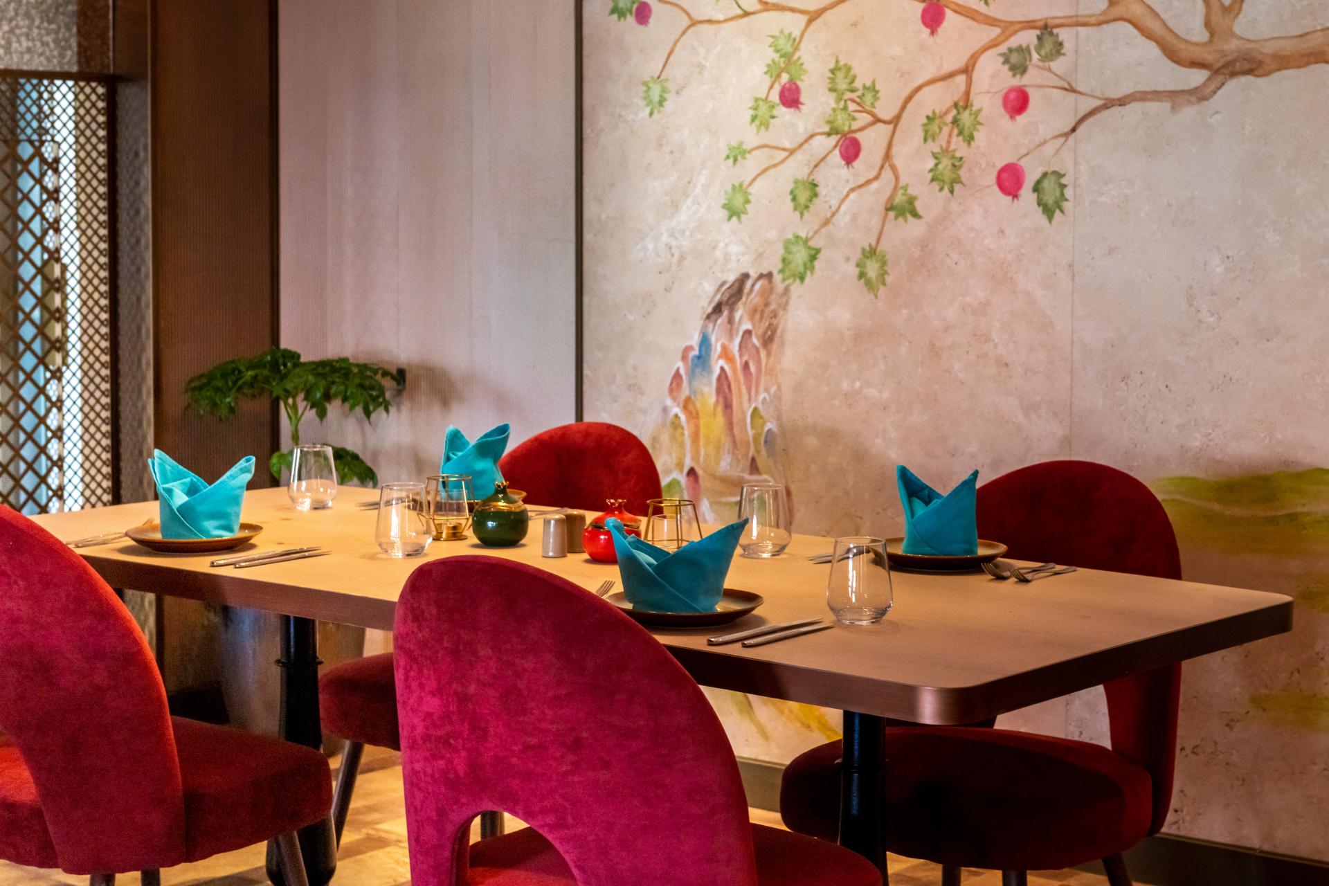 Elegant dining setup at Persian restaurant Anar, featuring colorful decor, vibrant table settings, and a beautiful mural.