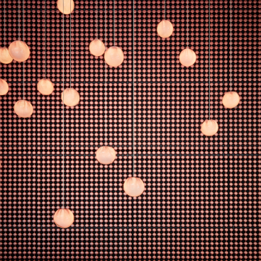 Hanging round lights illuminate a textured wall, showcasing the chic design aesthetic of Sir Victor hotel in Barcelona.
