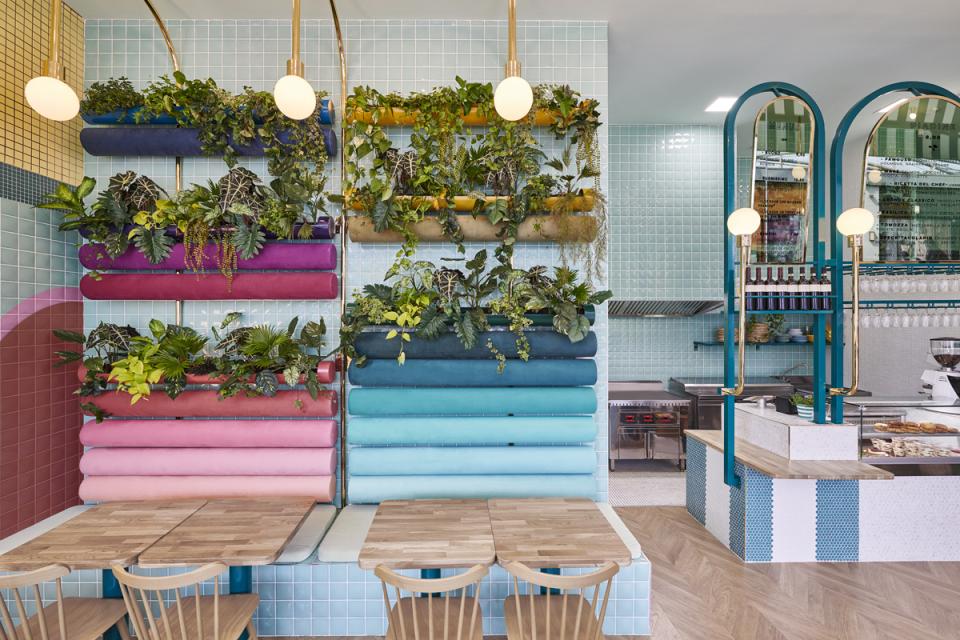 Vibrant indoor plants adorn colorful wall shelves in the stylish interior of Piada, an Italian restaurant in Lyon.