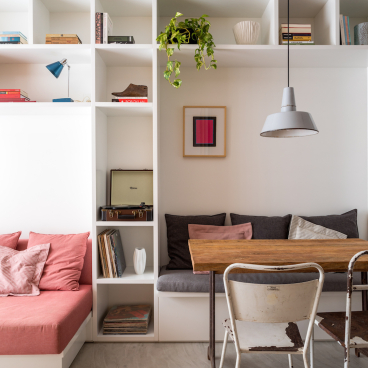 Cozy compact apartment interior designed by Leandro Garcia, featuring a stylish seating area and rustic dining table.