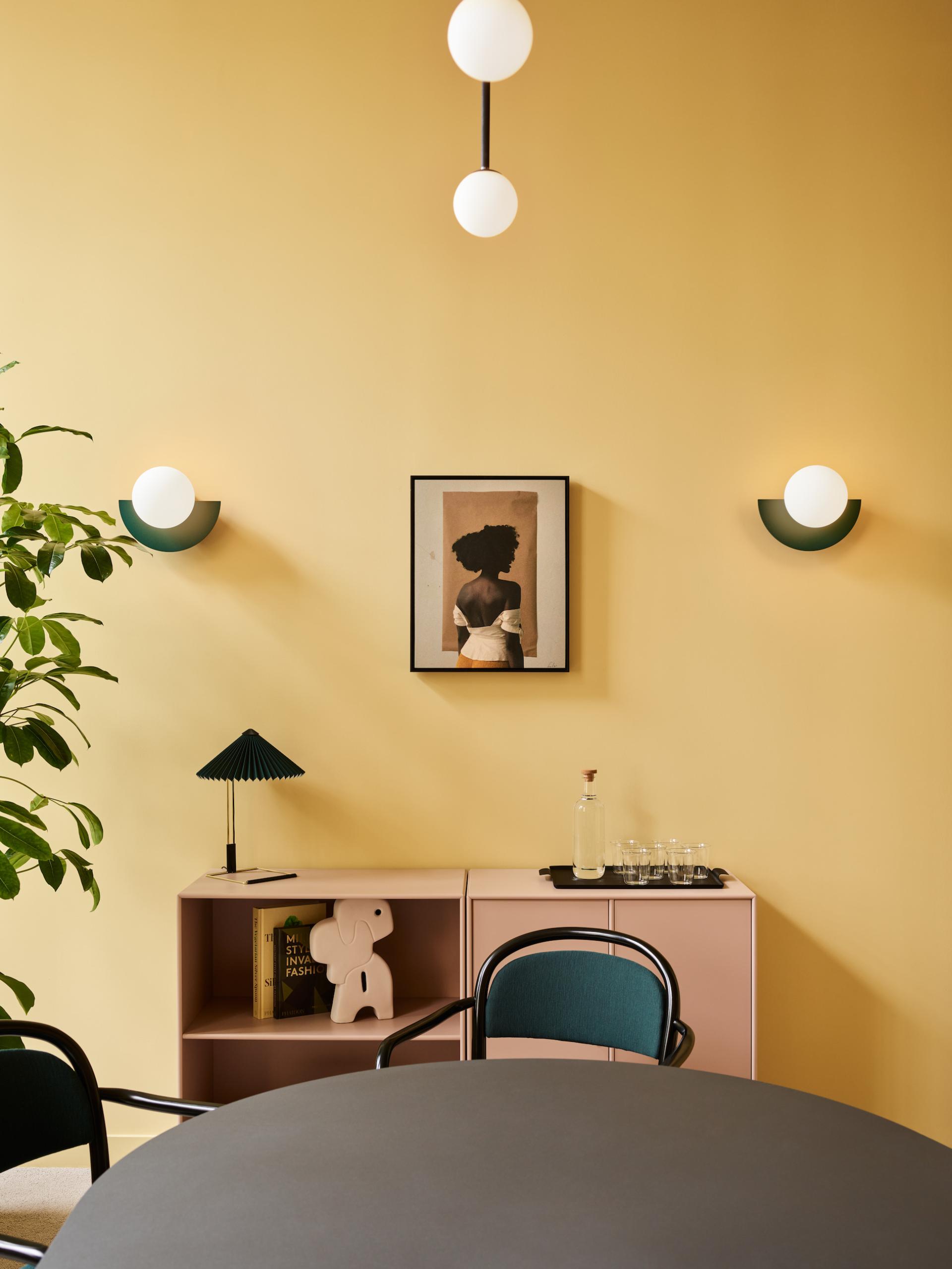 Modern workspace interior of Liberty House featuring a round table, decorative lighting, and artistic wall elements.
