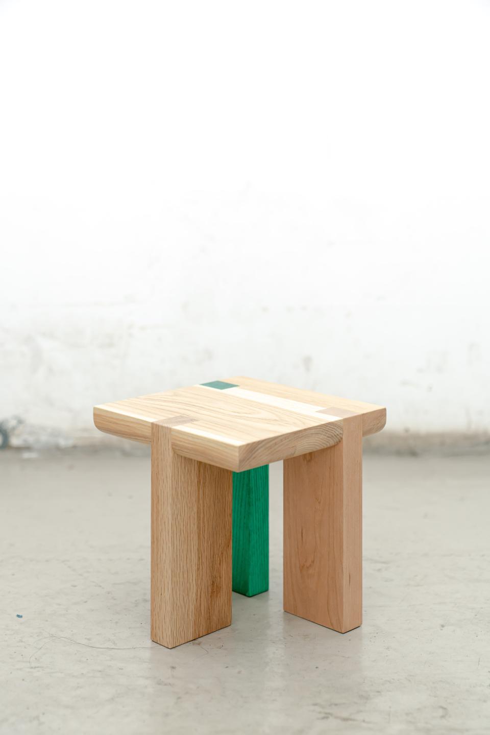 Stylish mini-stool featuring natural wood tones and a vibrant green leg, perfect for versatile home decor.