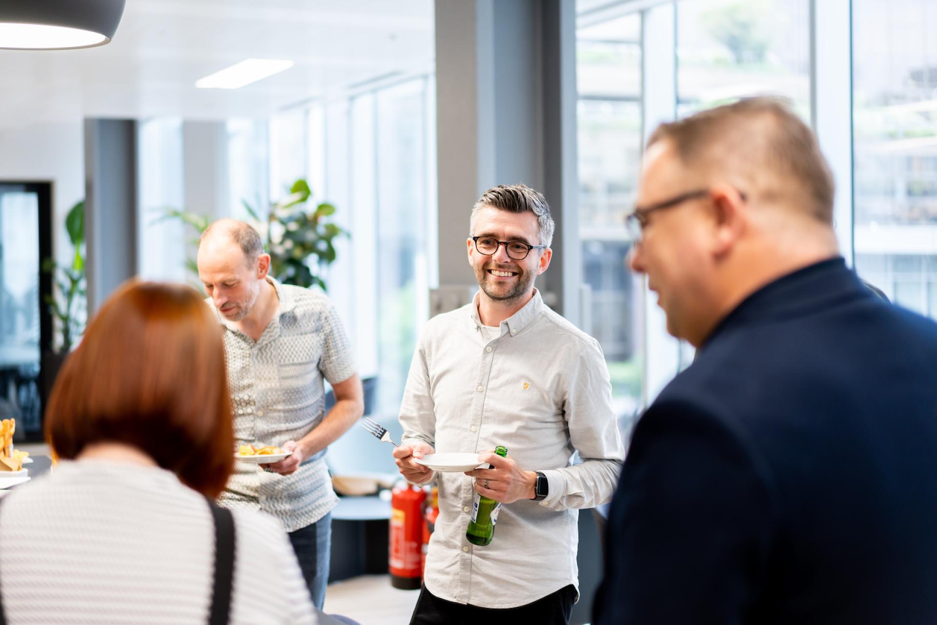 Employees socialize in a modern office environment, highlighting collaboration and technology in a forward-thinking workplace.