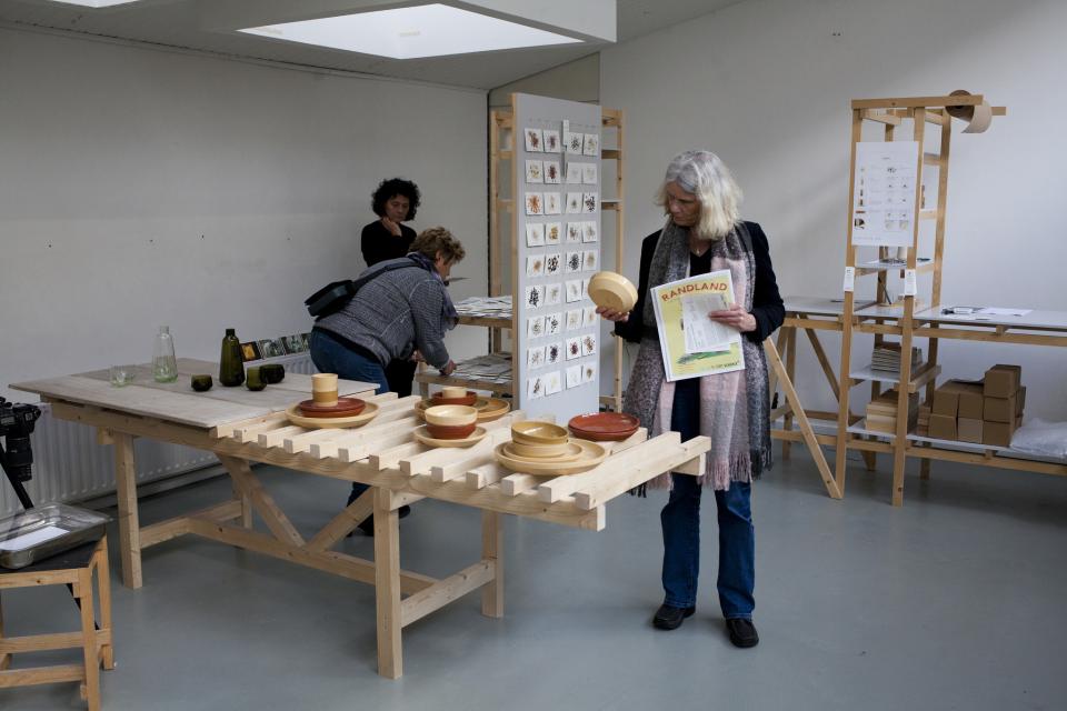 Visitors explore sustainable design displays featuring handmade ceramics and eco-friendly products at Dutch Design Week.