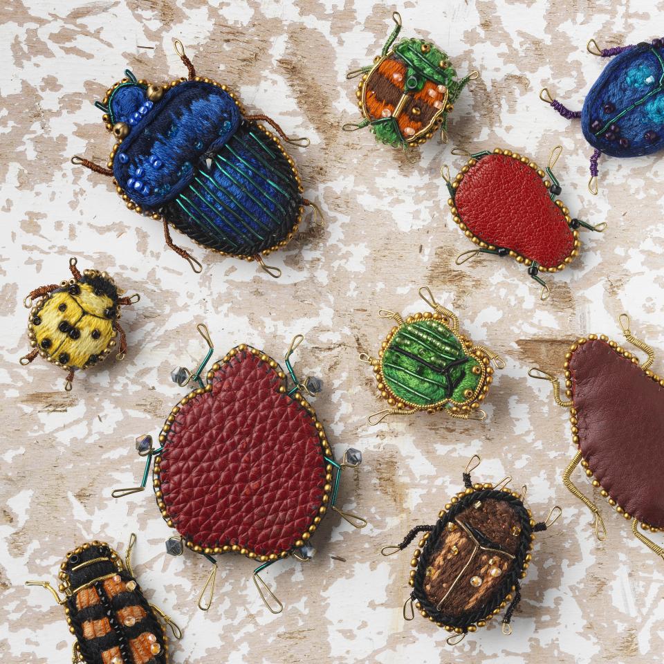 Colorful, handcrafted insect brooches displayed on a textured surface, showcasing the creativity of new designers from the Class of 2022.