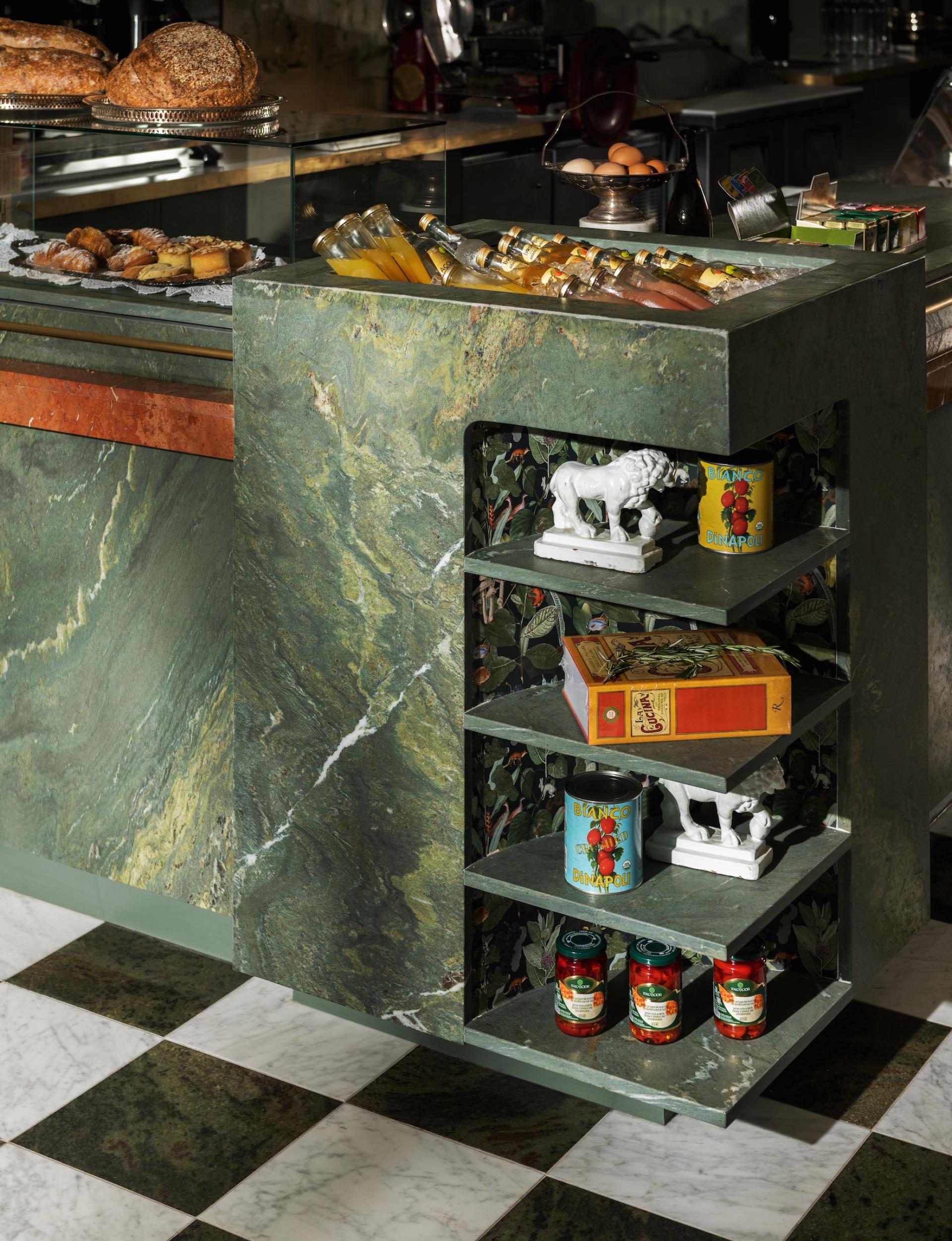 Stylish café counter featuring green marble, antique decor, and Italian products, showcasing old-world charm at Caffè La Tana.
