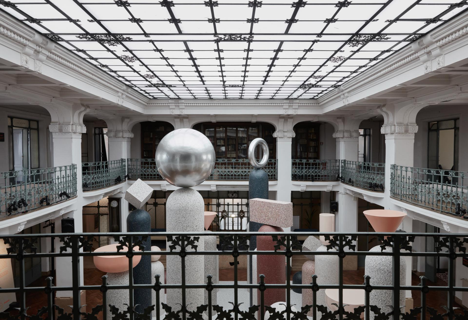 Artistic installation featuring geometric sculptures in a spacious, modern industrial setting at Milan Design Week.