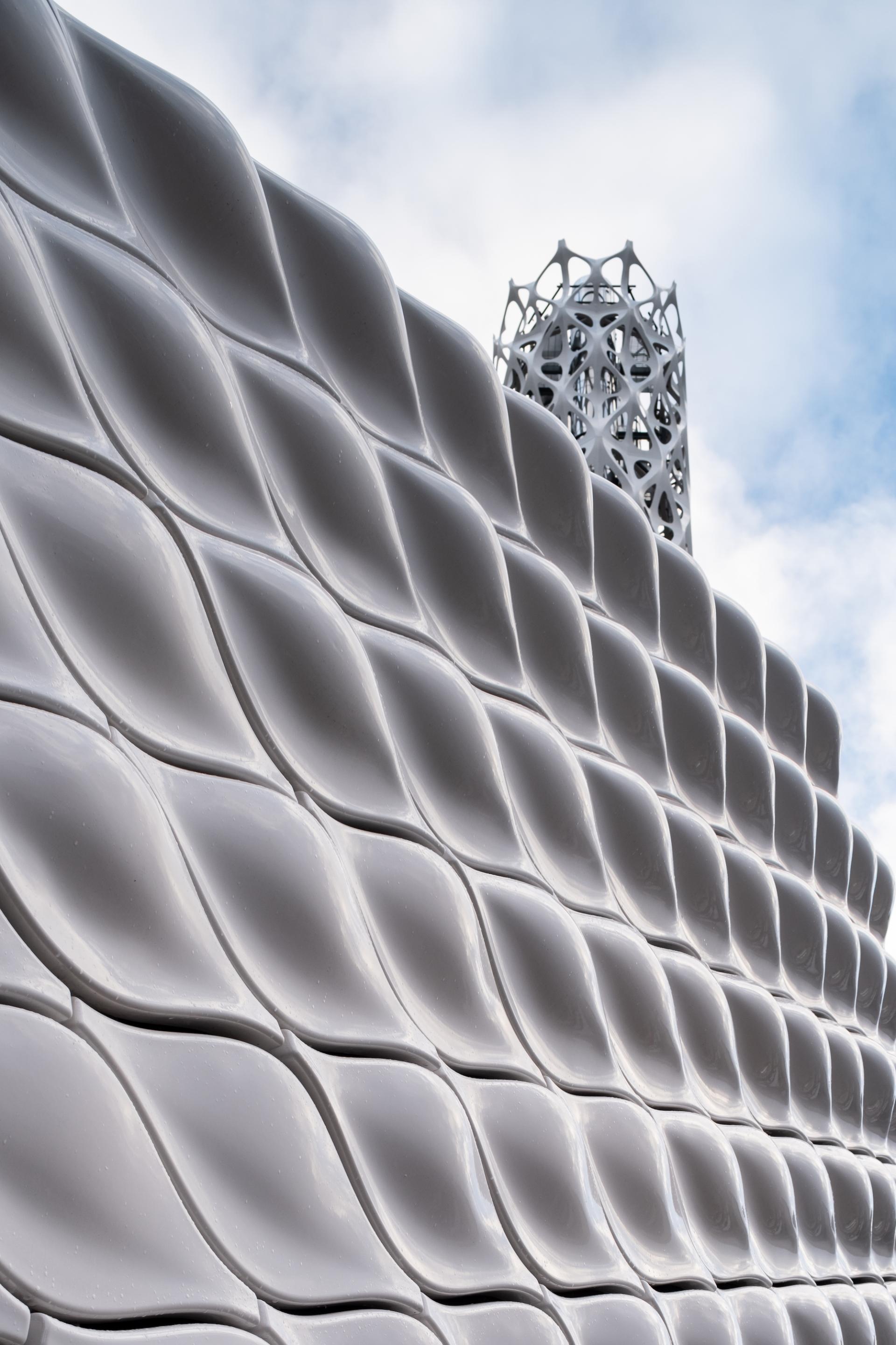 Textured white wall of Tonkin Liu’s Tower of Light, featuring energy-efficient design elements, set against a cloudy sky.