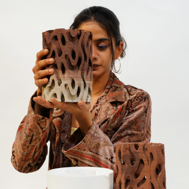 Rameshwari Jonnalagadda holding a clay 3D printed structure designed for efficient building cooling, showcasing innovative architectural solutions.