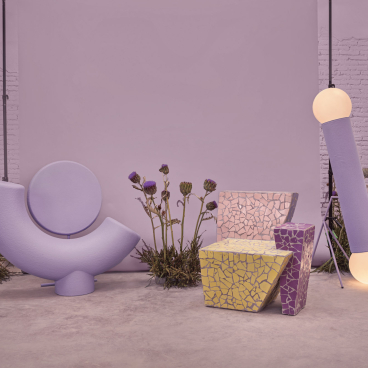 Colorful chairs and a lamp designed by Masquespacio, inspired by friendship, surrounded by flowers in a modern setting.