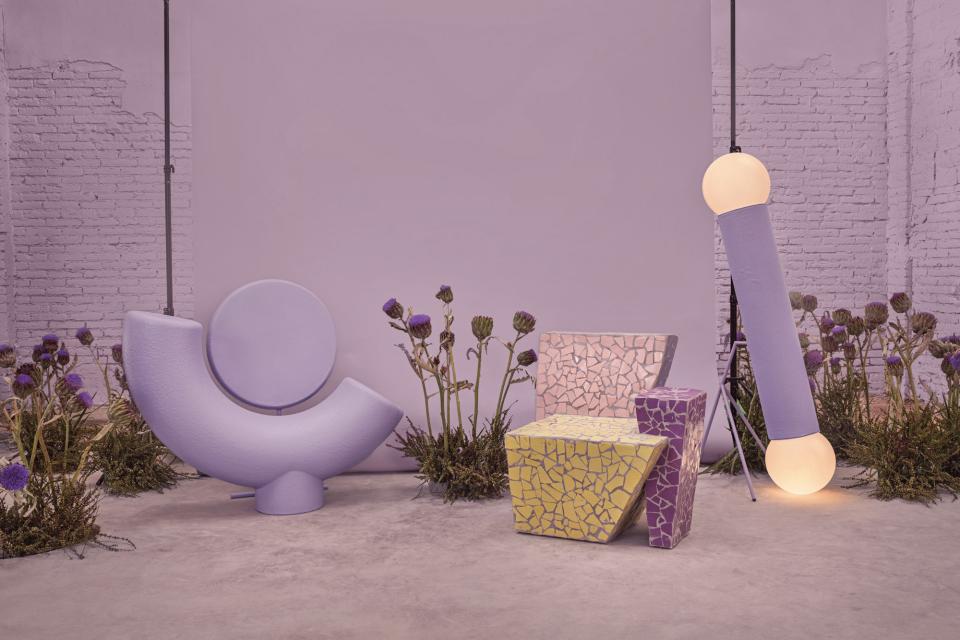 Colorful chairs and a lamp designed by Masquespacio, inspired by friendship, surrounded by flowers in a modern setting.
