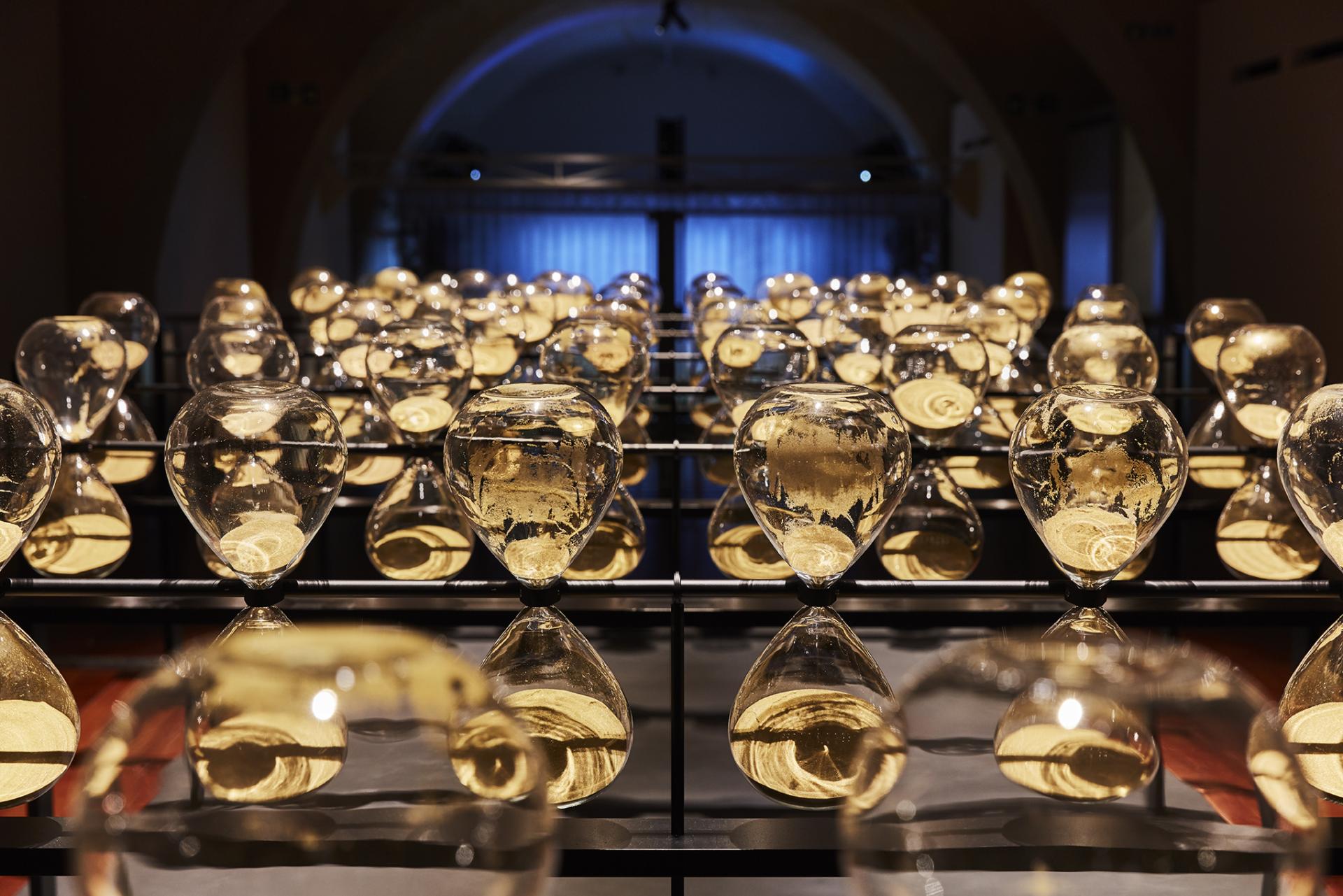 Colorful hourglass sculptures arranged in a grid, showcasing innovative design at the London Design Biennale in Somerset House.