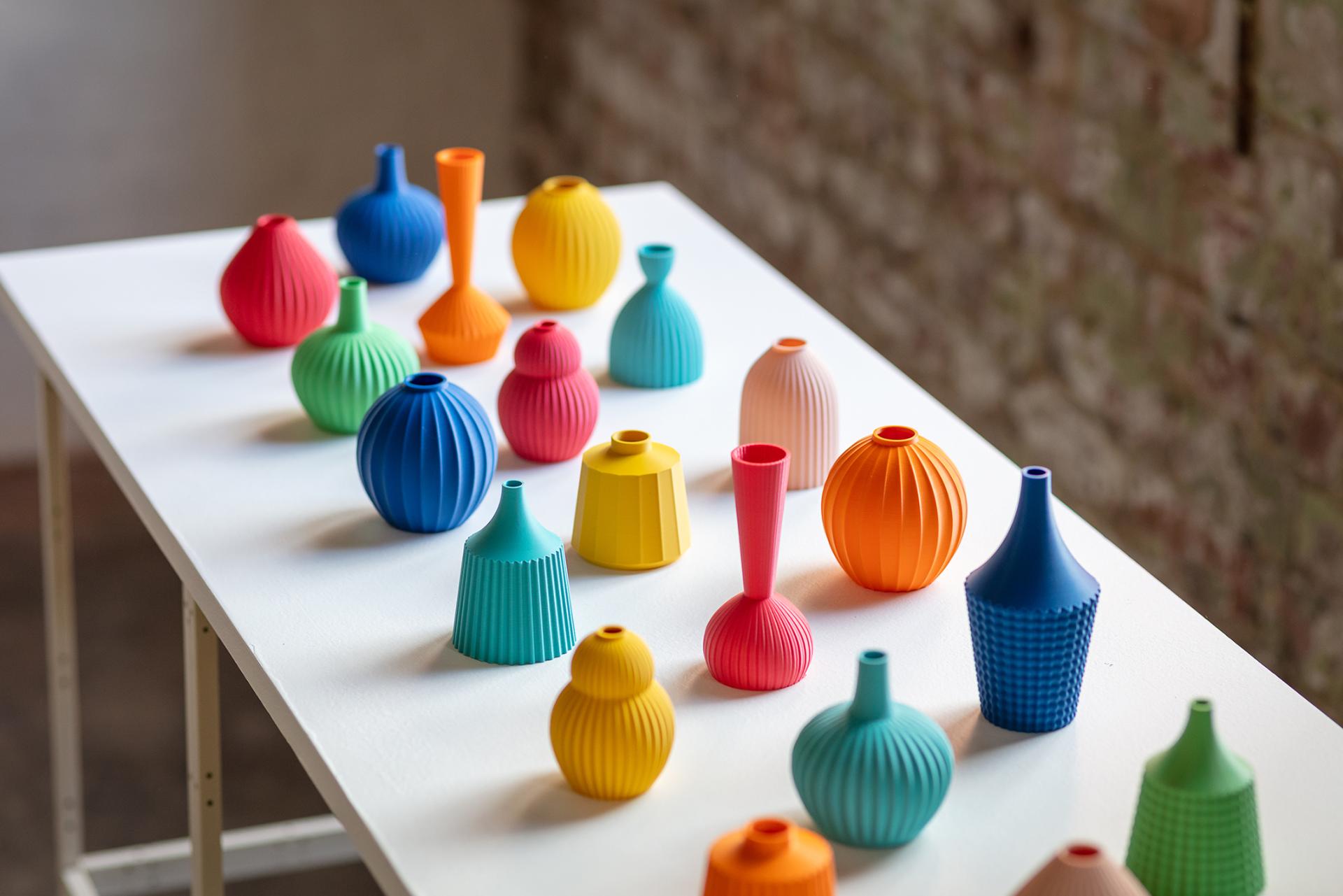 Colorful ceramic vases in various shapes and sizes displayed on a white table at Made in the Middle exhibition.