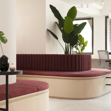 Modern office workspace featuring curved seating, indoor plants, and a minimalist design for Charterhouse's Asia office.