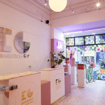 Colorful interior of Edinburgh Gin pop-up store features candy coral terrazzo flooring and vibrant floral window display.