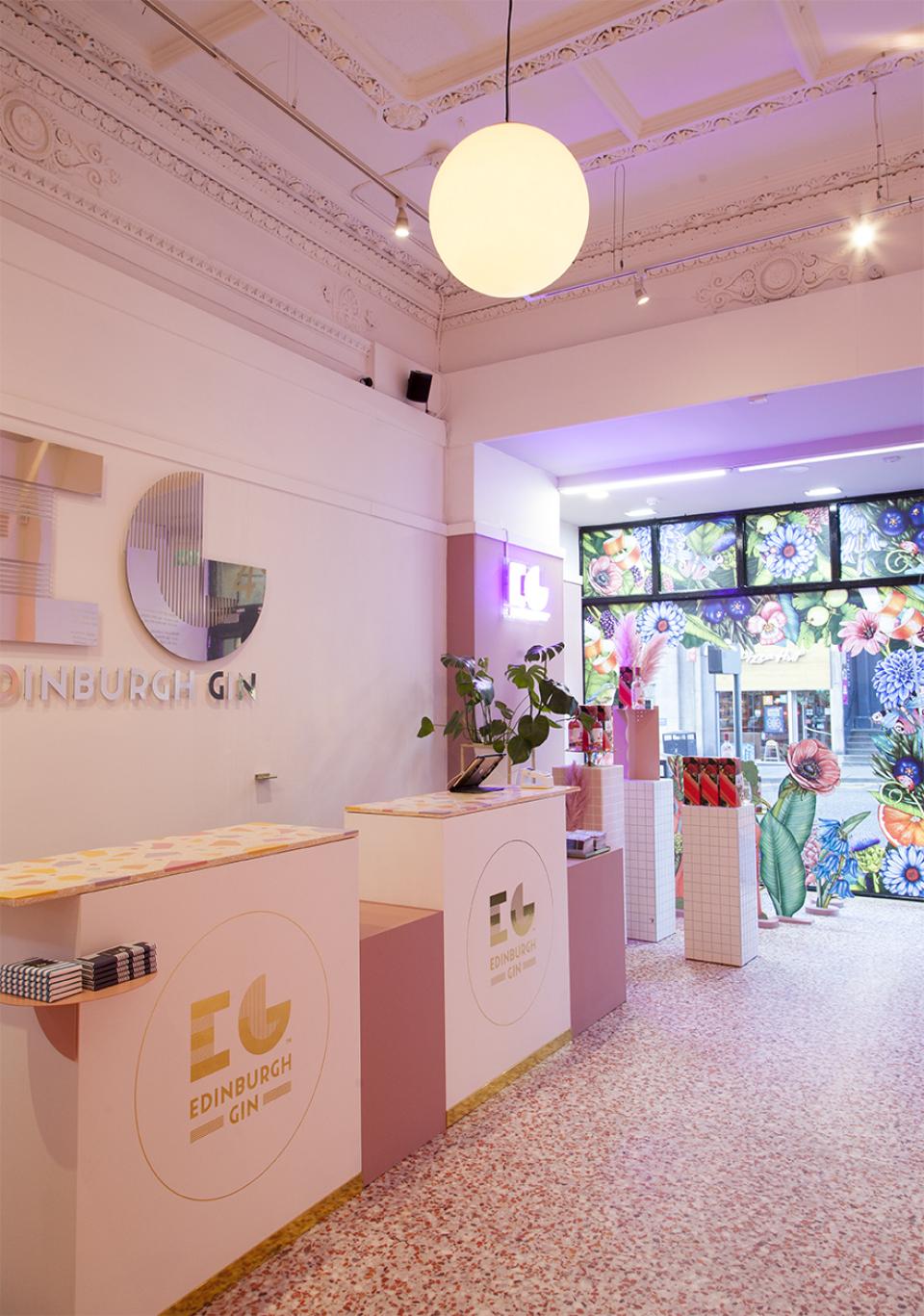 Colorful interior of Edinburgh Gin pop-up store features candy coral terrazzo flooring and vibrant floral window display.