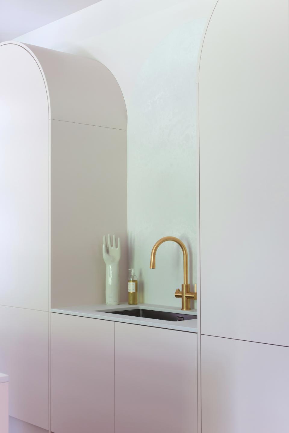 Modern kitchen design featuring sleek cabinetry, a gold faucet, and a stylish decorative hand sculpture.