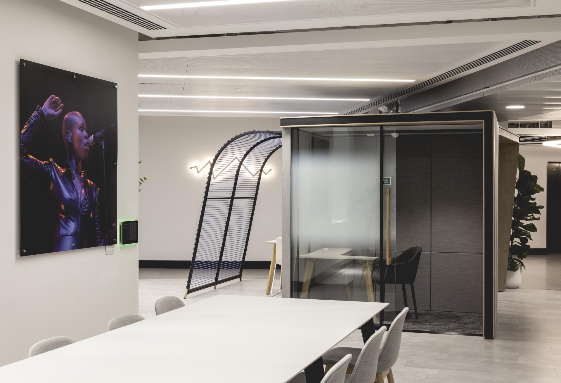 Modern office interior featuring a vibrant music-themed artwork, sleek furniture, and multi-use collaborative spaces.