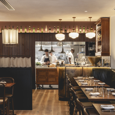 Stylish interior of Studio Found's Fitzrovia restaurant, blending Parisian chic with rustic British decor, featuring chefs at work.